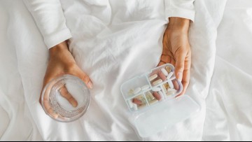 a woman in bed with a pill case and a glass of water