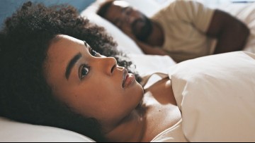 woman having sleep troubles and man sleeping in bed