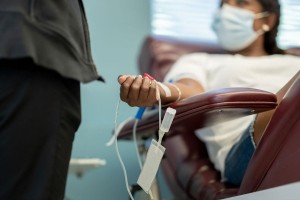 Woman sitting back in a chair with a tourniquet and IV in as she donates blood. (Getty Images/FatCamera)