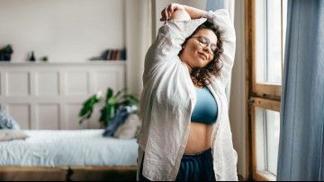 happy woman stretching in front of window