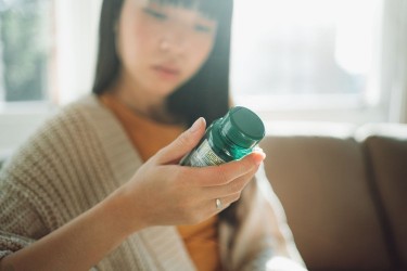 woman looking at supplement bottle