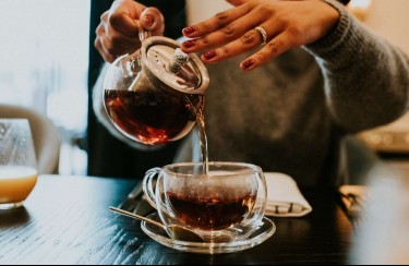 hand pouring cup of tea