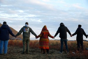 Water protectors join hands in prayer at the end of the day's protest as police line the hill at Standing Rock on Nov. 24, 2016, during an ongoing dispute over the building of the Dakota Access Pipeline. (Jessica Rinaldi/The Boston Globe via Getty Images)