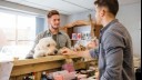 white dog looking over counter top with owner and clerk