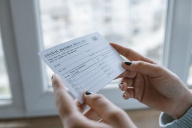 female hands holding covid vaccination card