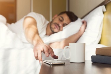 Man snoozing his alarm