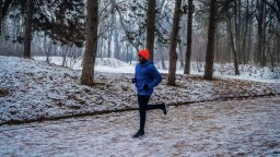 A man runs on a trail in a snowy forest