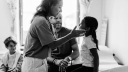 A female doctor checks a young girl while her father watches