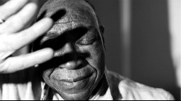 black and white photo of older Black man shielding his face with his hand