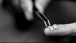 A person holding microdoses of LSD with a pair of tweezers on their fingers