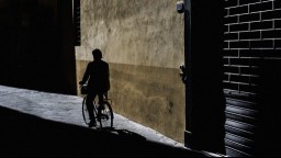 Silhouette of person riding a bike on a sidewalk