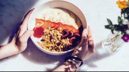 A breakfast granola bowl with cherries, strawberries, and bananas on a bed of yogurt