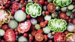 An array of different types of tomatoes cut open to show their insides and colors