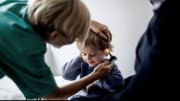 A doctor checks the ear of a young child