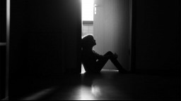 The silhouette of child sitting in a doorway of a dark hall