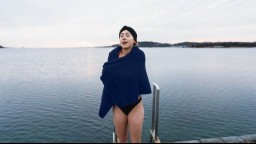 woman emerging from cold water wrapping herself in blue towel