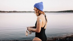 A woman wearing a glucose monitoring patch prepares to swim in a lake