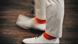 close-up of tapping feet clad in white leather shoes and red socks