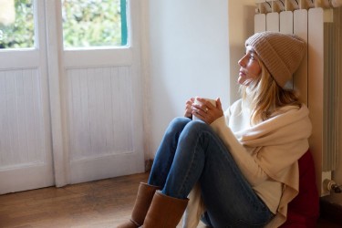 Woman leaning against a heater