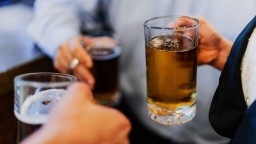 Glasses of beer are held by three people