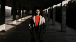 A younger African-American woman strolls along an underpass