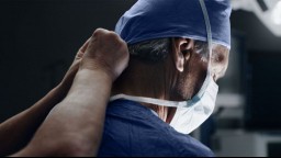 A medical assistant puts a mask on a surgeon