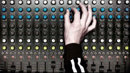 A hand turns up a knob on an audio board