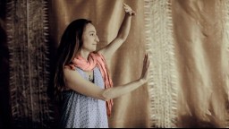 A woman practicing tai chi against a fabric backdrop.