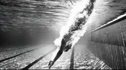 An underwater photo of a woman diving into a swimming pool