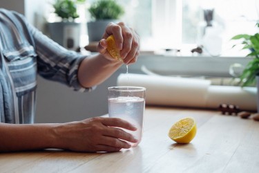 woman squeezing lemon into water