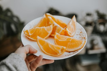 Woman holding plate of orange slices