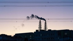 Dark smoke rises from an industrial chimney