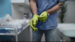 A surgeon puts on light green latex gloves