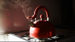 red kettle letting out steam on a stove